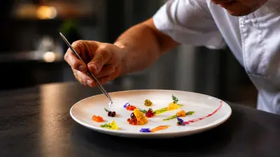 Chef emplatando con pinzas un plato de autor