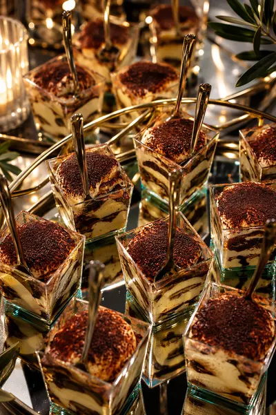 Tiramisú servido en vasitos de cristal con cucharas doradas